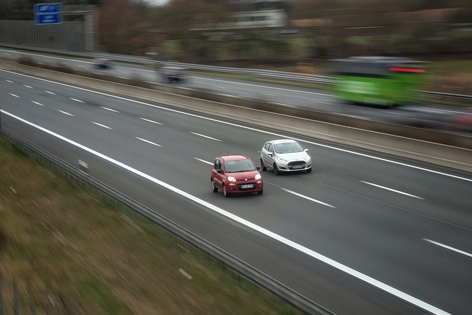 Two cars moving fast on a highway, showcasing speed and travel in motion.